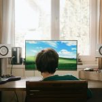 boy in red shirt sitting on chair in front of black flat screen tv